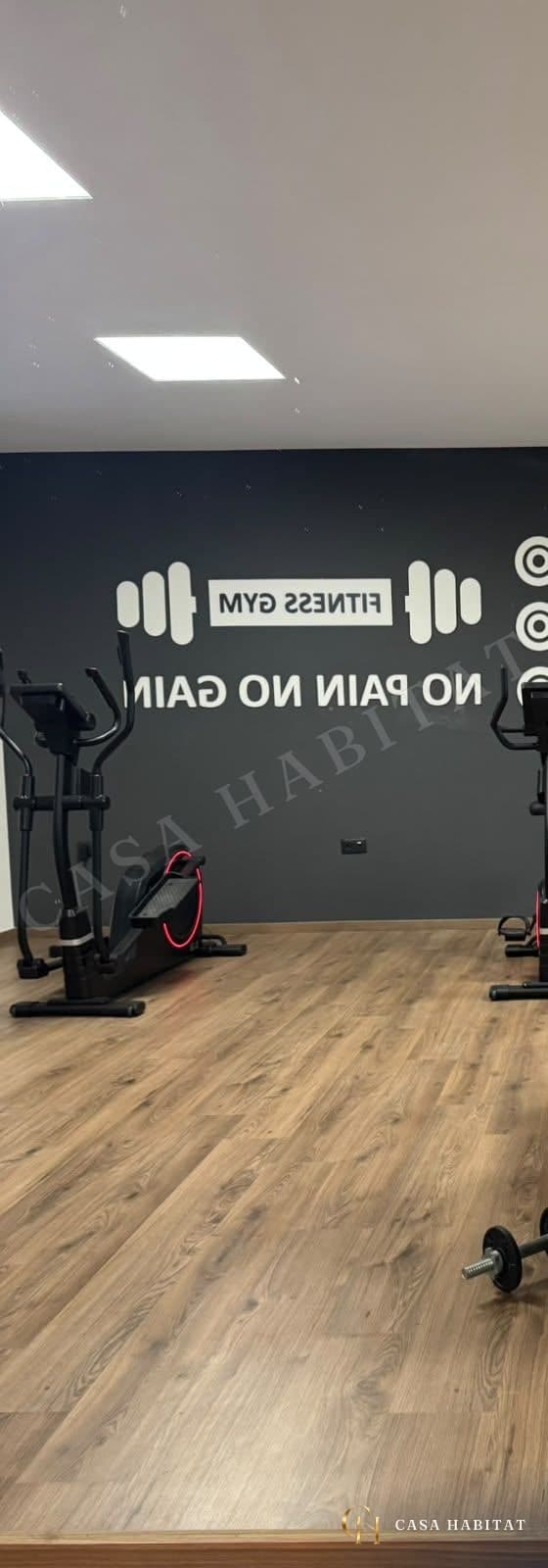Salle de sport avec vélo elliptique et tapis en bois