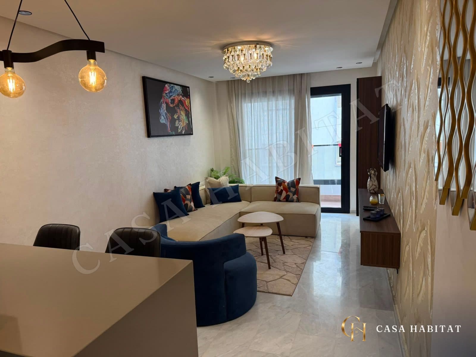 Salon avec canapé beige, fauteuil bleu et téléviseur mural