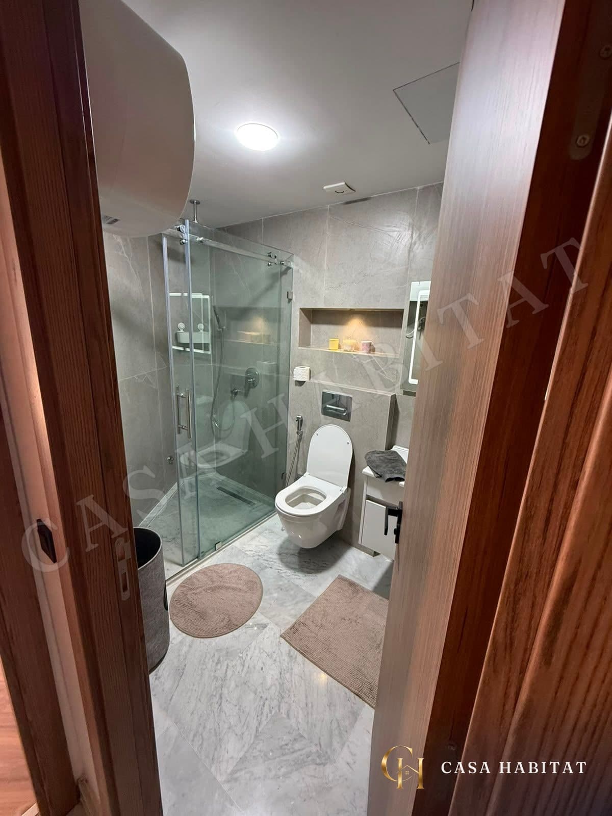 Salle de bain avec douche en verre, WC suspendu et sol en marbre