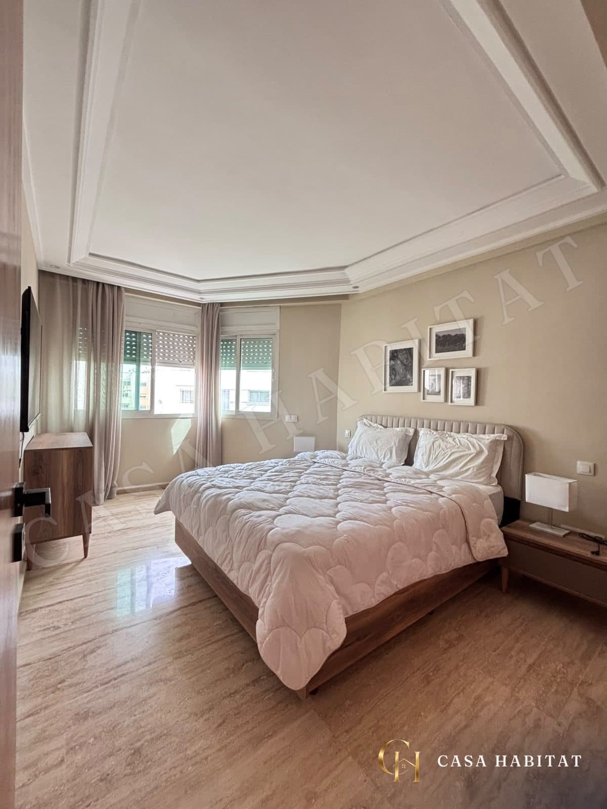 Chambre avec lit double, tête de lit capitonnée et fenêtres à volets