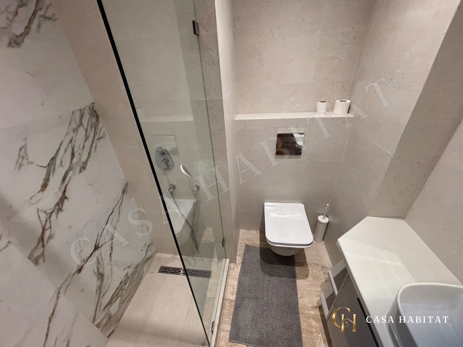 Salle de bain avec parois de douche vitrées et lavabo blanc