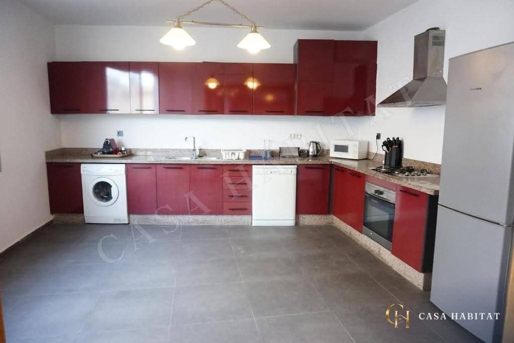 Cuisine avec armoires rouges, lave-linge et plaque de cuisson