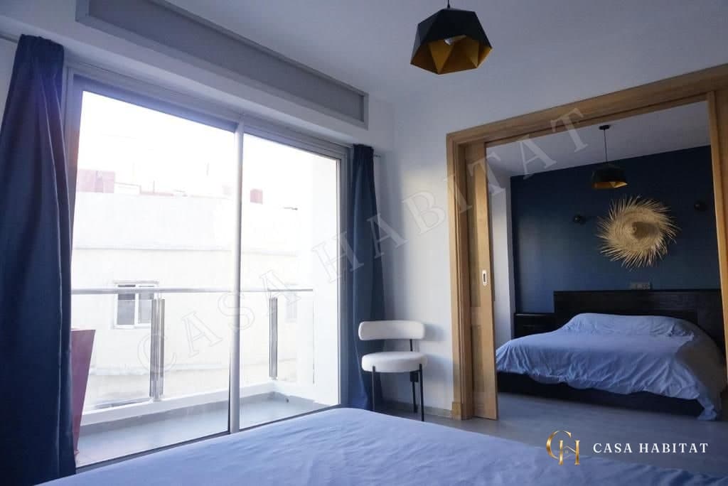 Chambre avec baie vitrée, rideaux bleus et chaise blanche