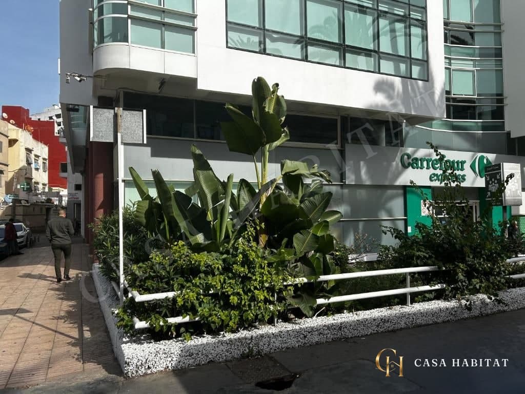 Façade d'immeuble avec plantes et enseigne de supérette