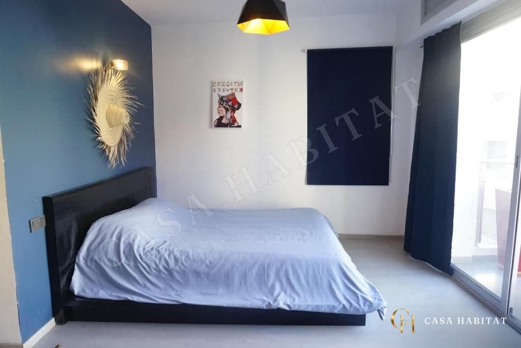 Chambre avec lit, mur bleu, suspension noire et dorée, porte-fenêtre