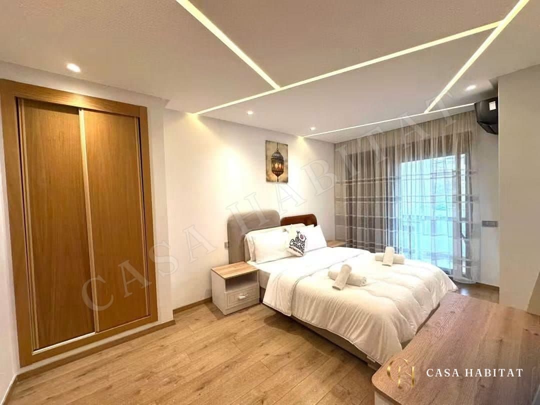 Chambre avec lit blanc, armoire en bois et plafond à LED