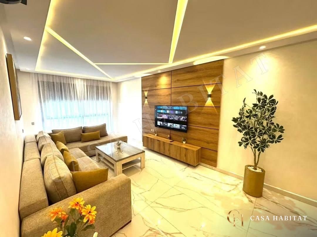 Salon avec canapé beige, plafond lumineux et plante verte