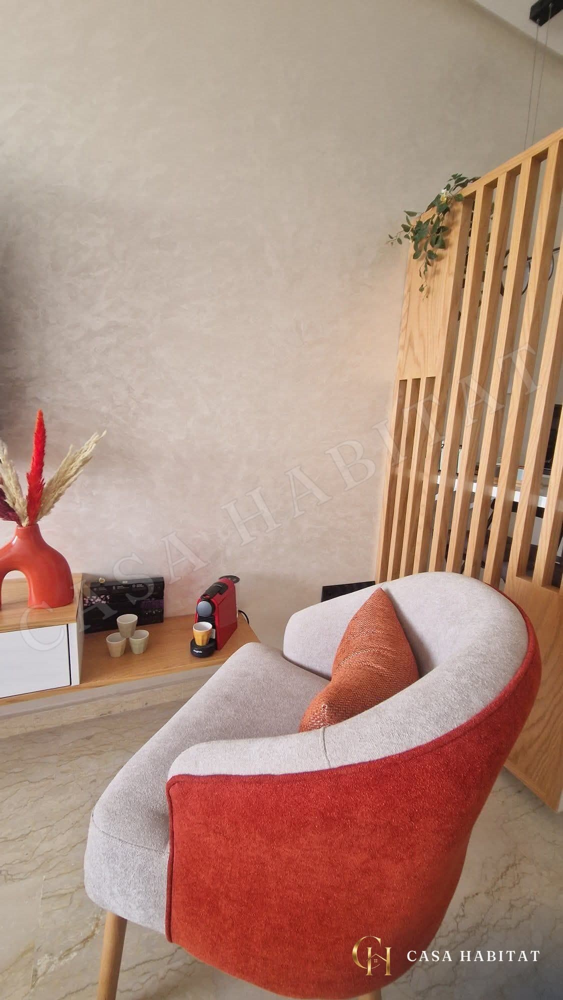 Coin salon avec fauteuil orange, machine à café et cloison en bois