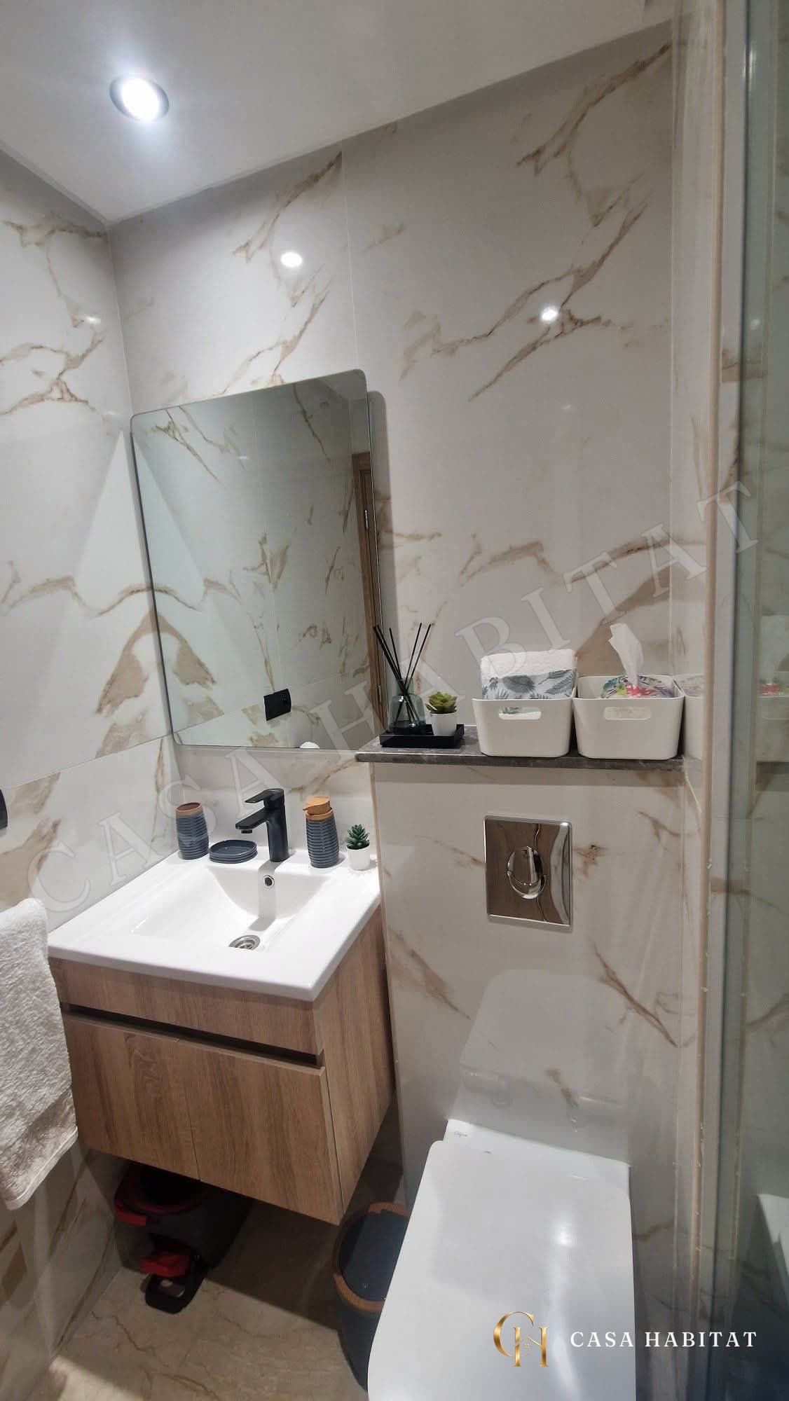 Salle de bain avec vasque en bois, miroir et murs effet marbre