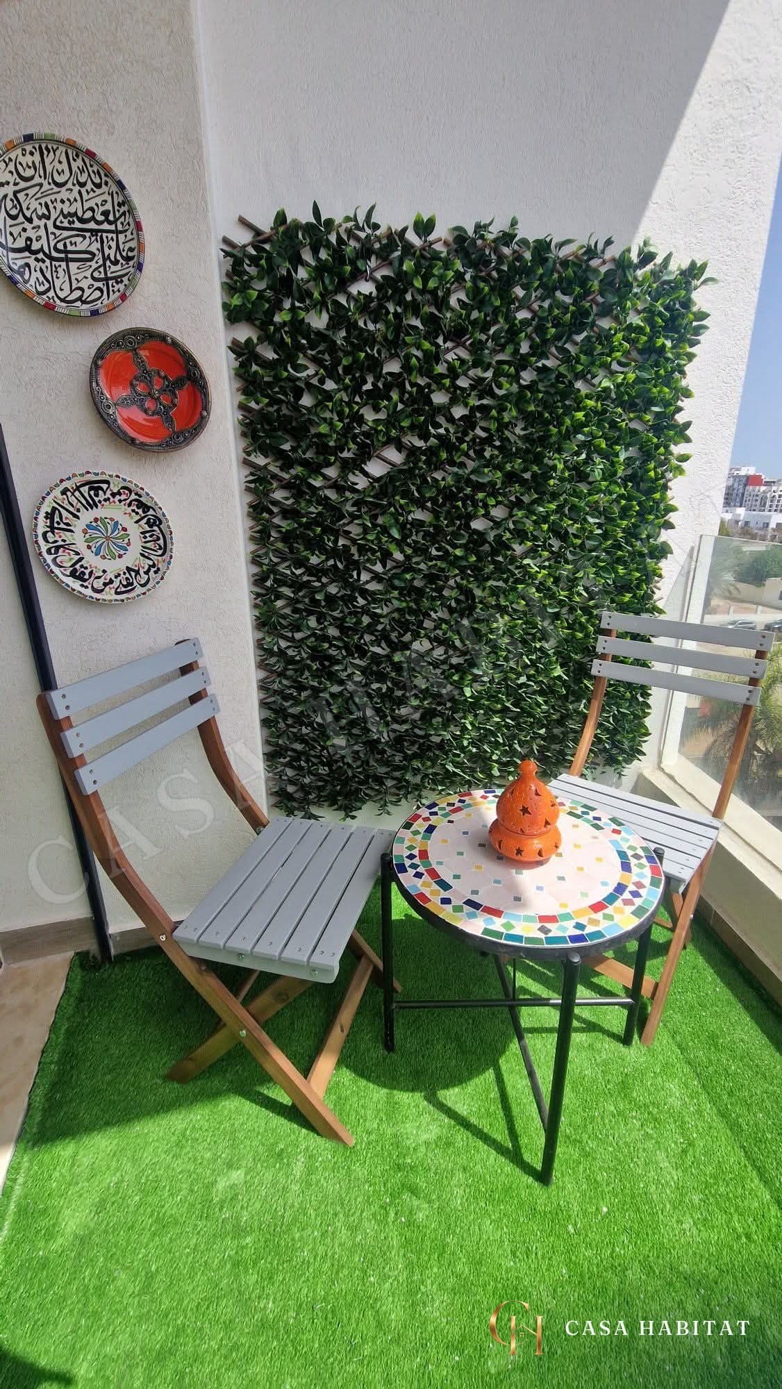 Balcon avec deux chaises pliantes, table en mosaïque et mur végétal