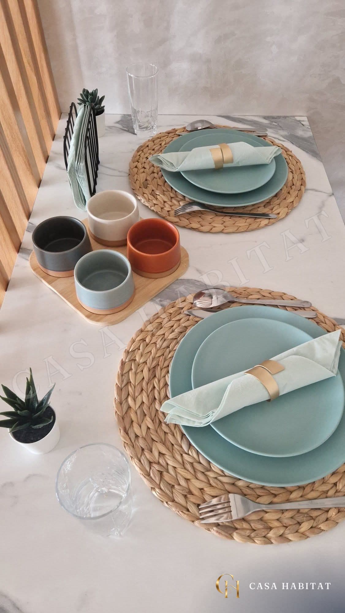 Table dressée avec assiettes bleues, sets en osier et bols colorés
