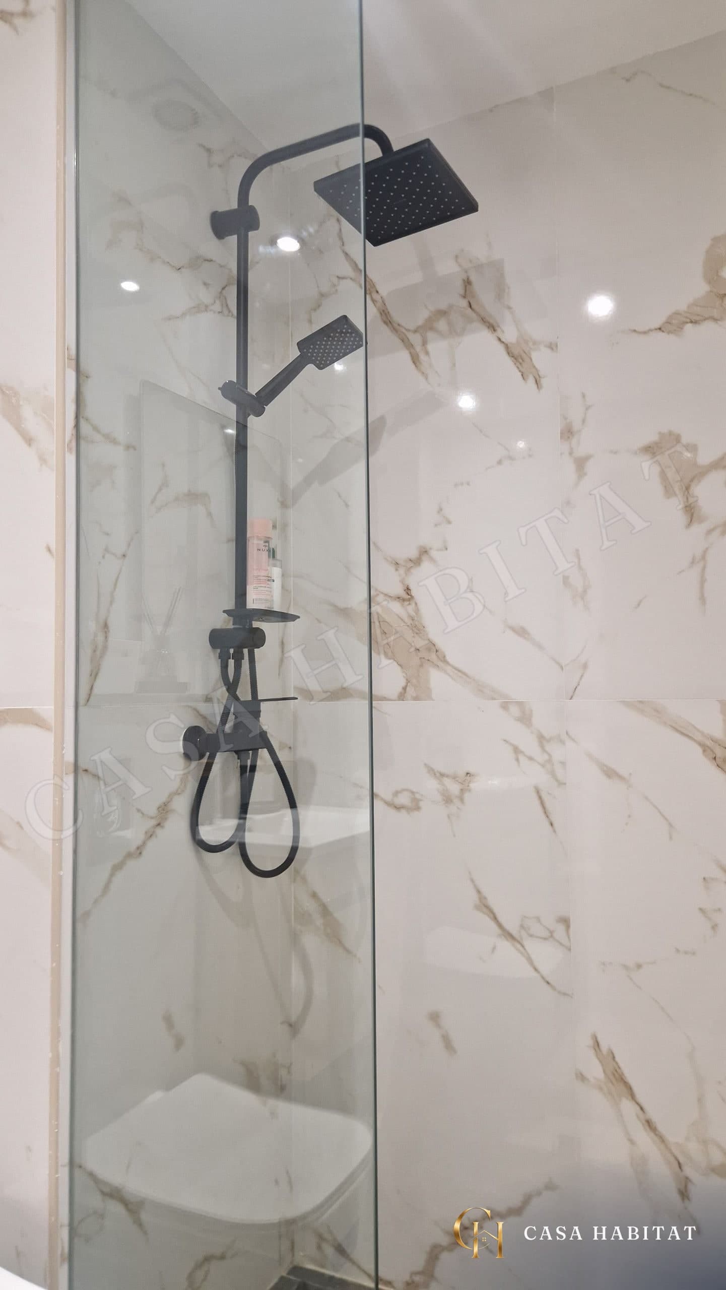 Douche avec colonne noire et paroi en verre, carrelage marbré