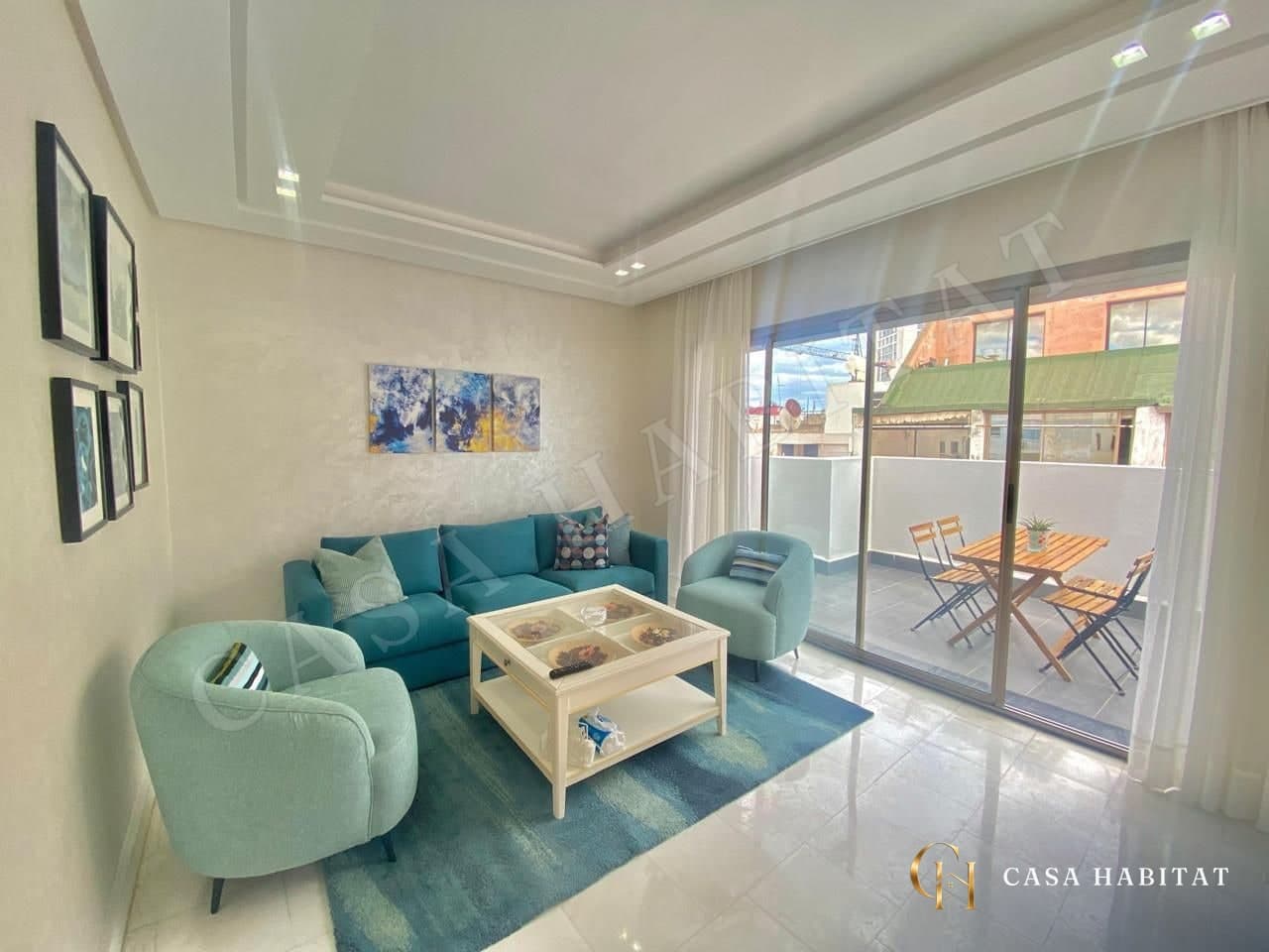 Salon avec canapé bleu, fauteuils turquoise et table basse blanche