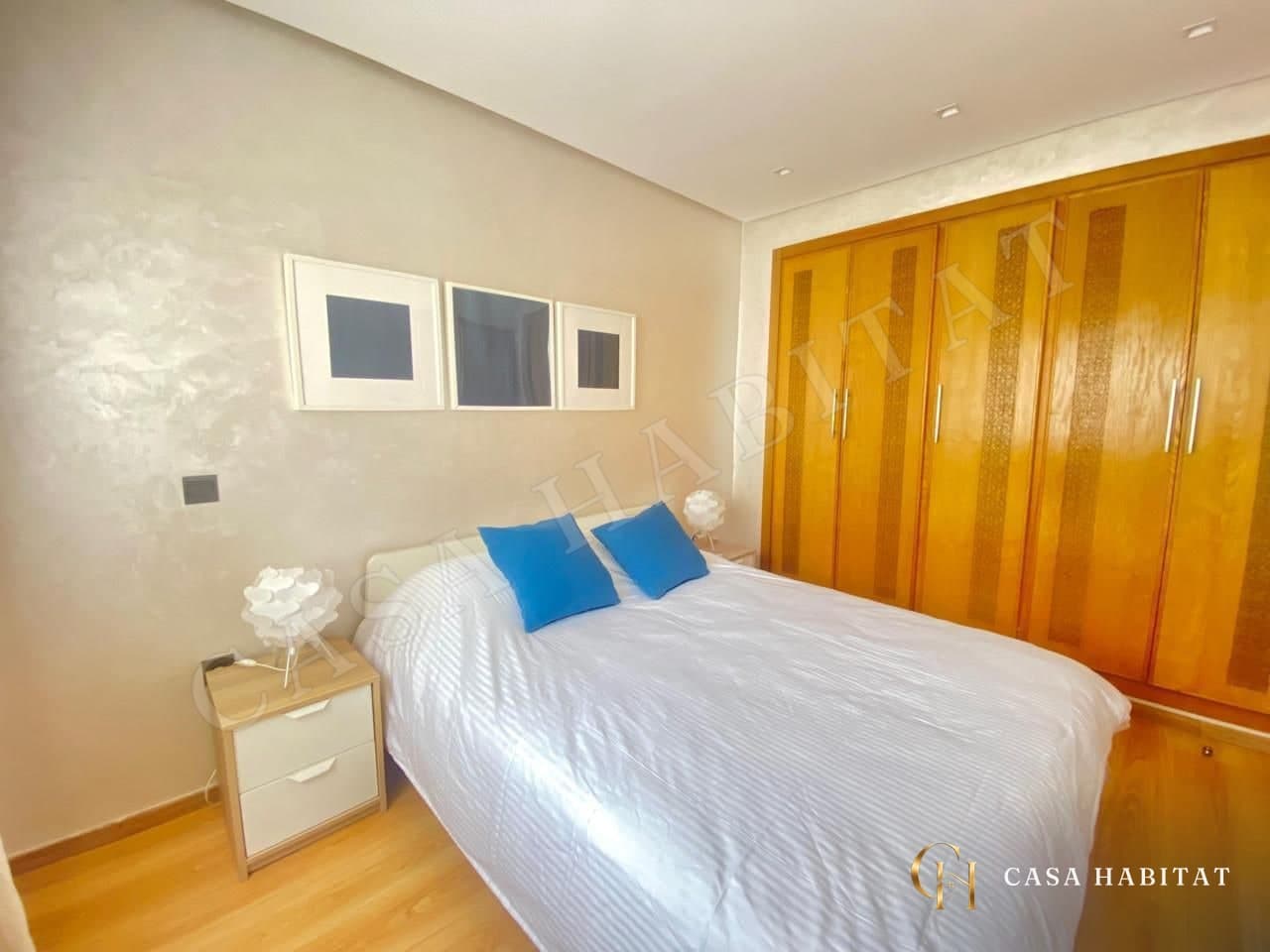 Chambre avec lit blanc, placard en bois et tableaux noir et blanc