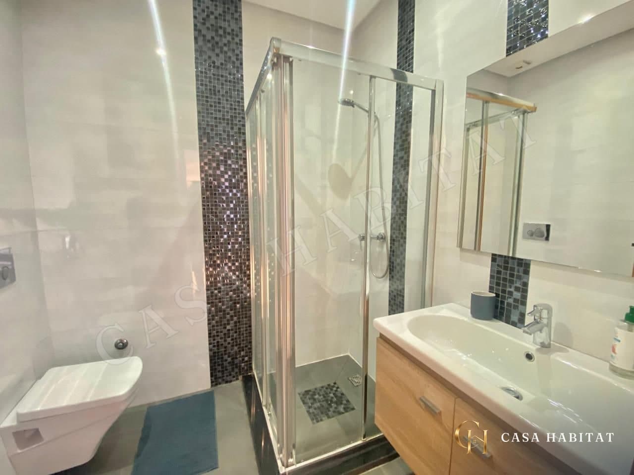 Salle de bain avec douche en verre, mosaïque et lavabo en bois