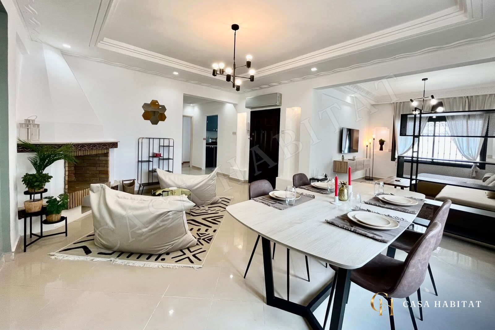 Salon et salle à manger avec table dressée et poufs beiges