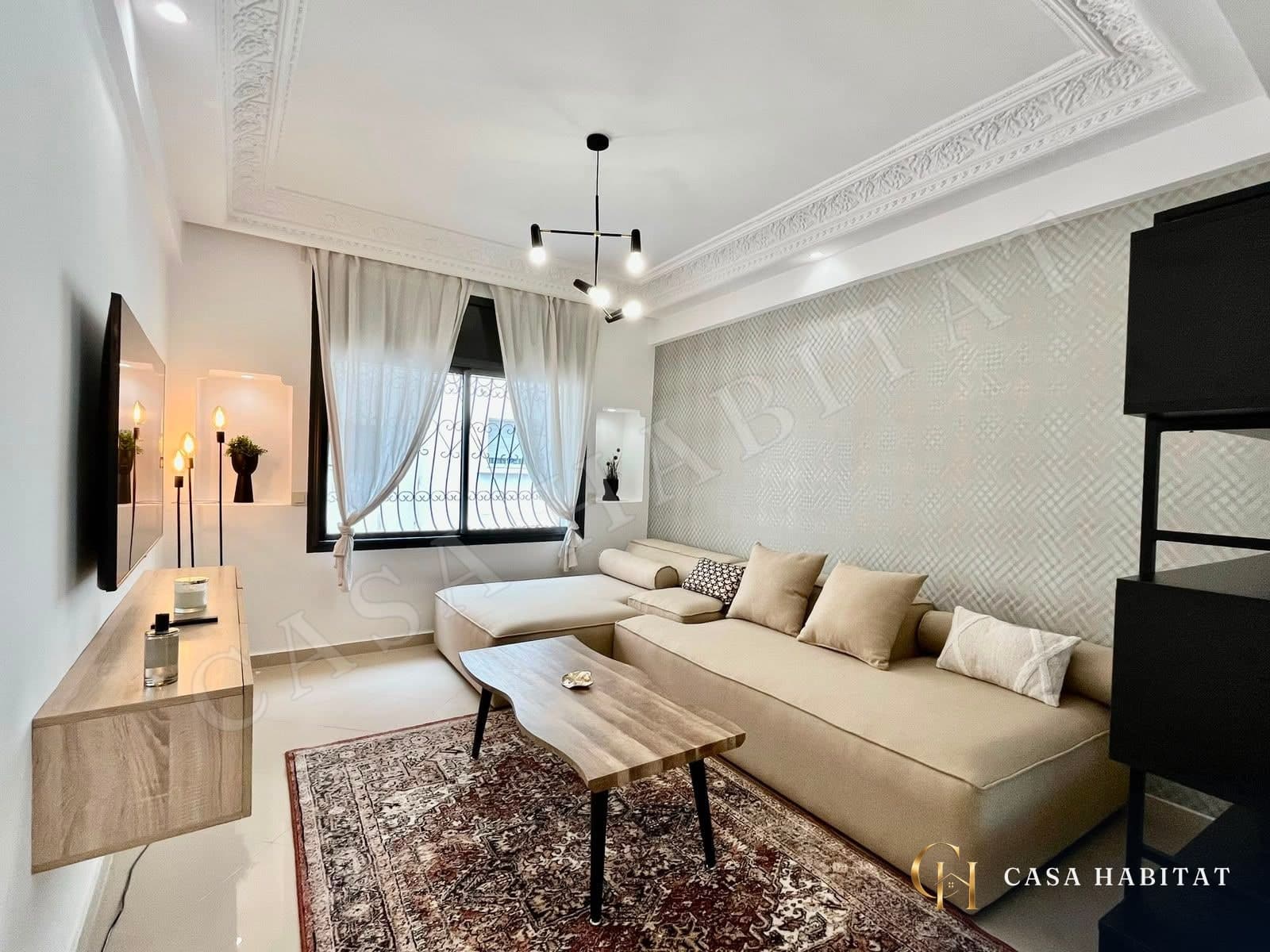 Chambre avec canapé beige pliable, table basse en bois et tapis