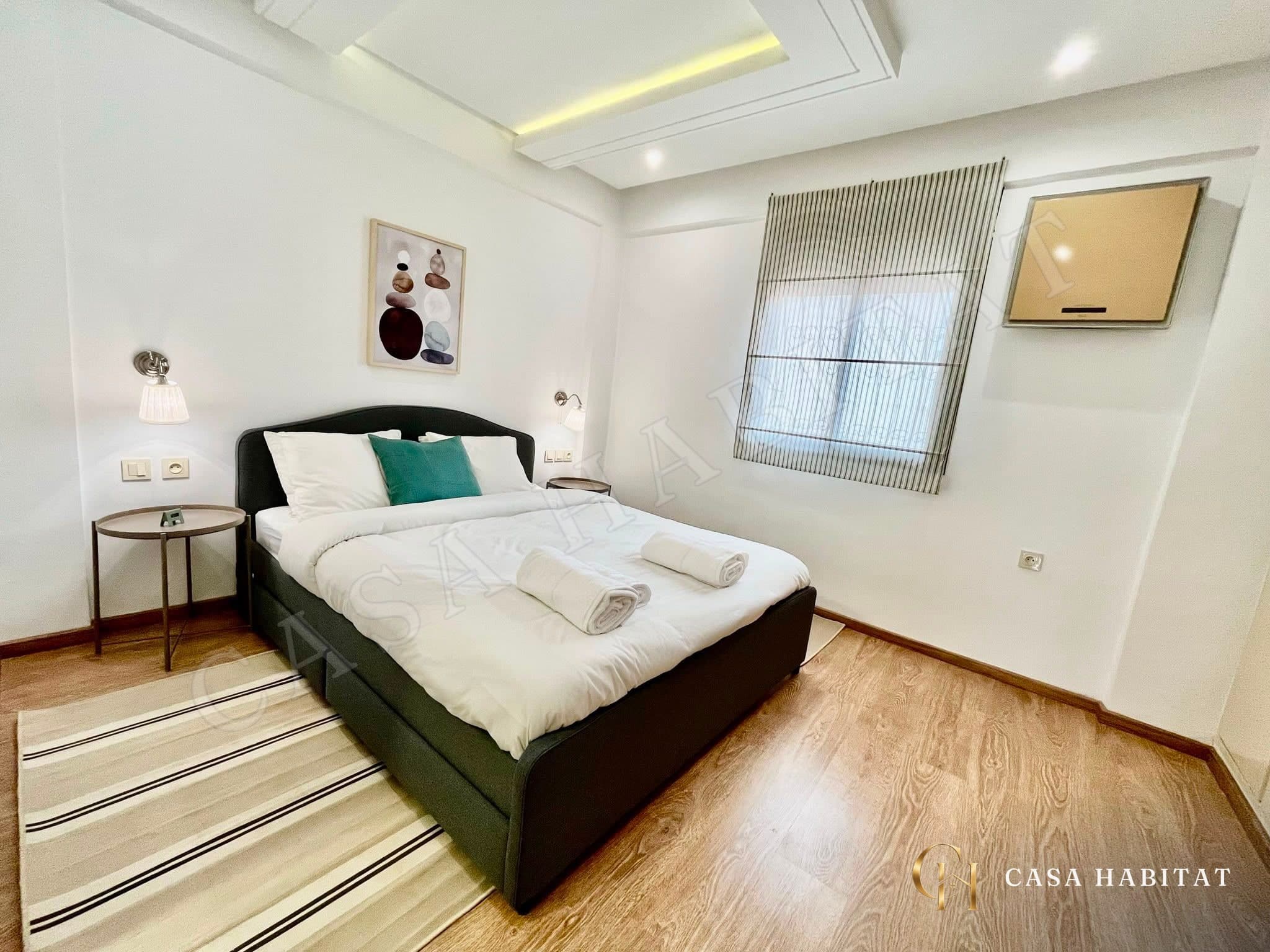 Chambre avec lit double, linge blanc et tableau mural