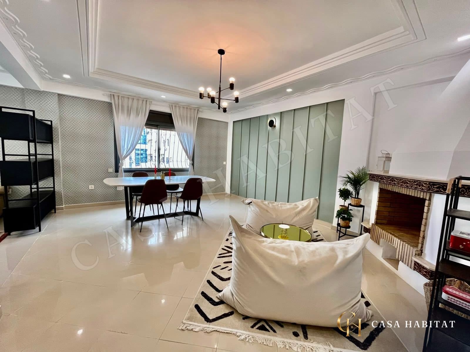 Salon avec table à manger, poufs et cheminée en briques