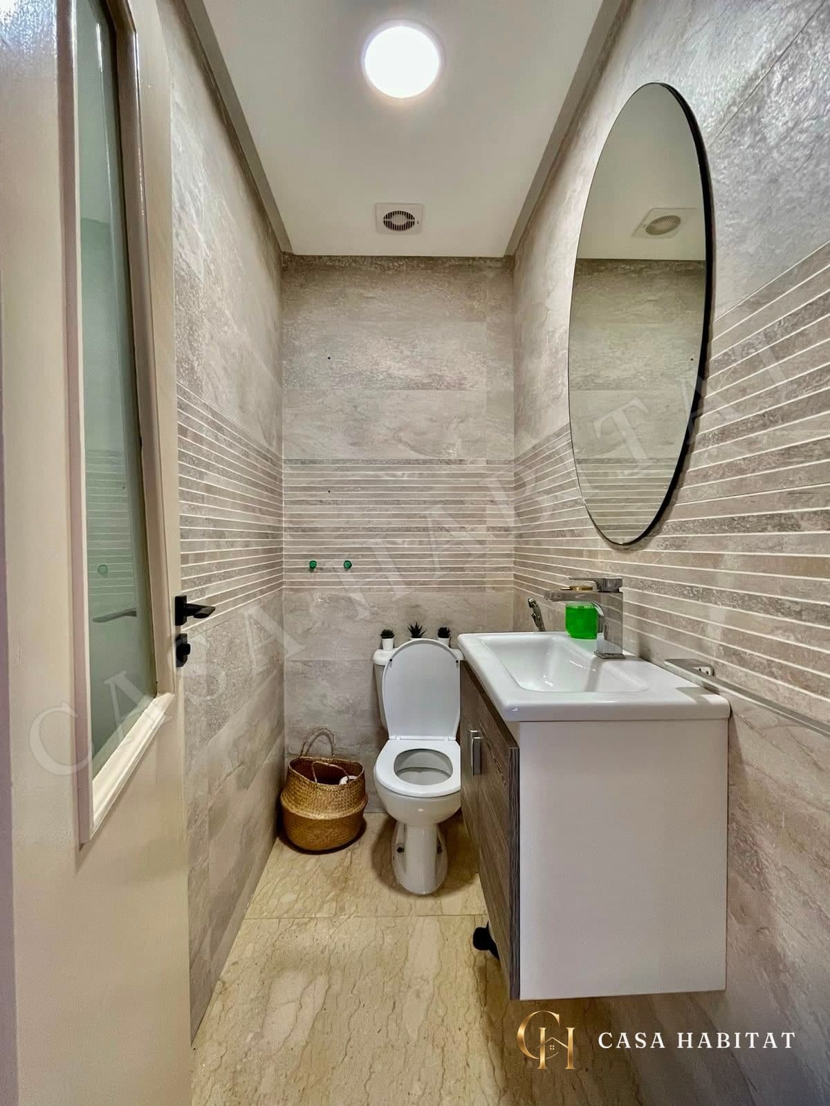 Salle de bain avec lavabo suspendu et miroir rond