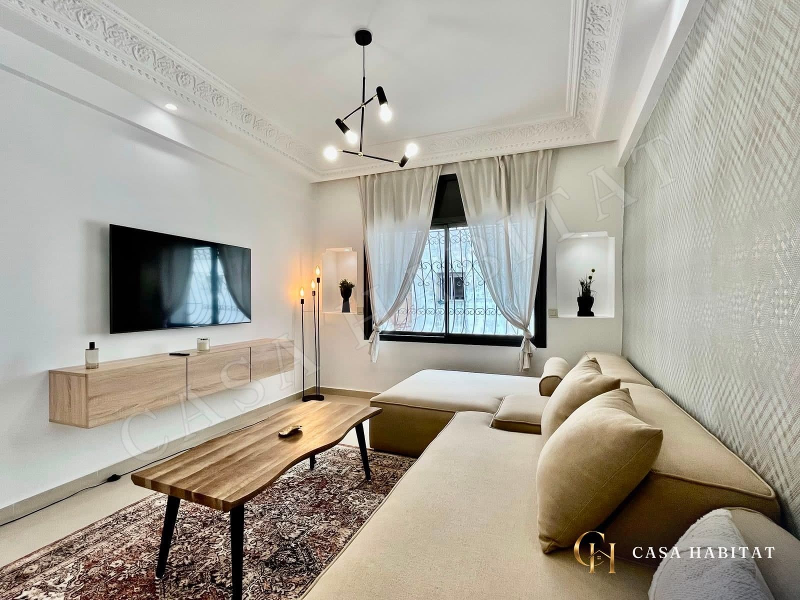 Chambre avec meuble TV suspendu, canapé beige et tapis