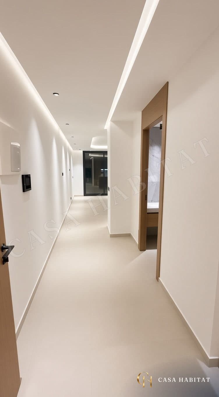 Couloir clair avec spots au plafond, porte en bois et salle de bain