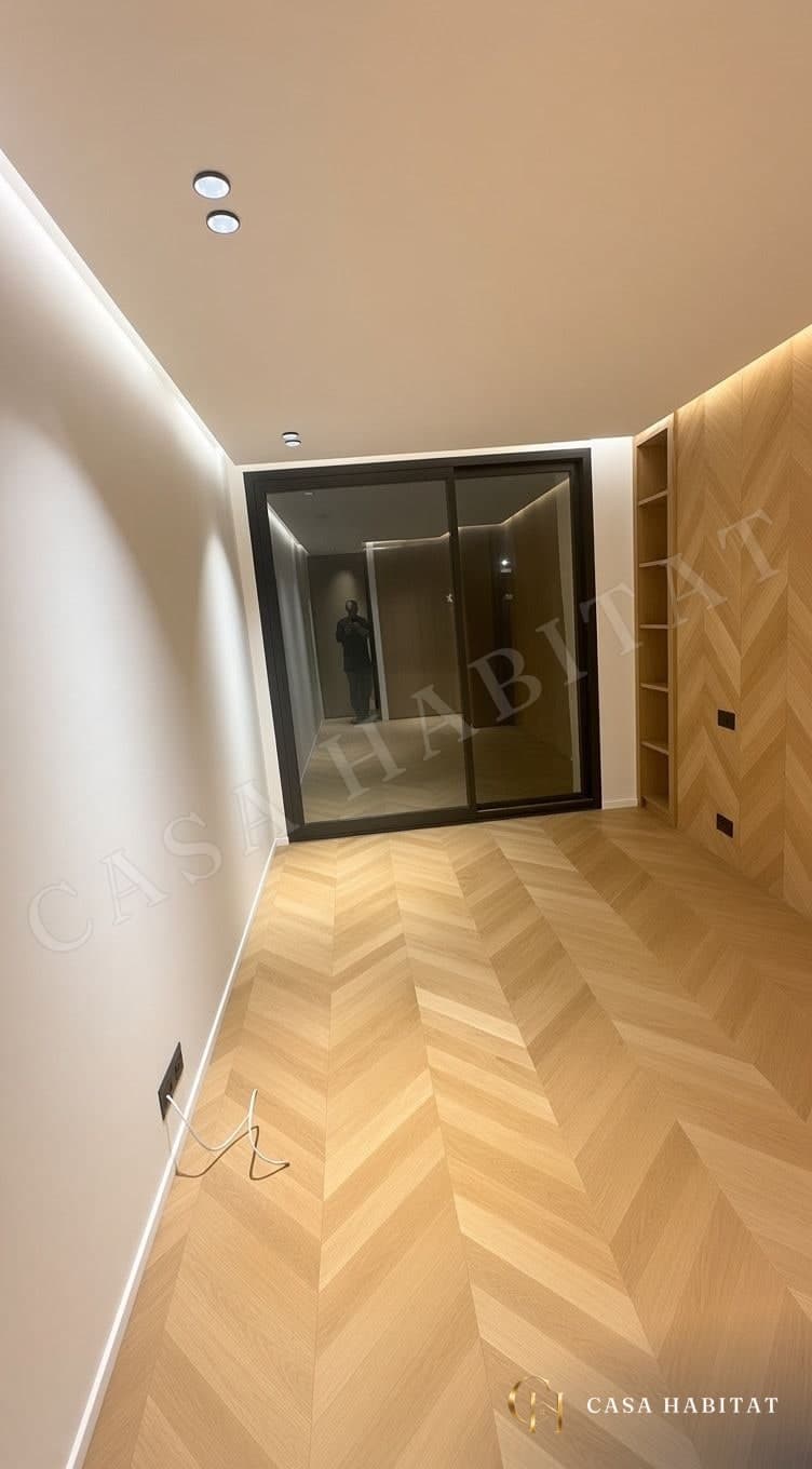 Pièce au parquet en chevron clair, placards en bois et baie vitrée noire