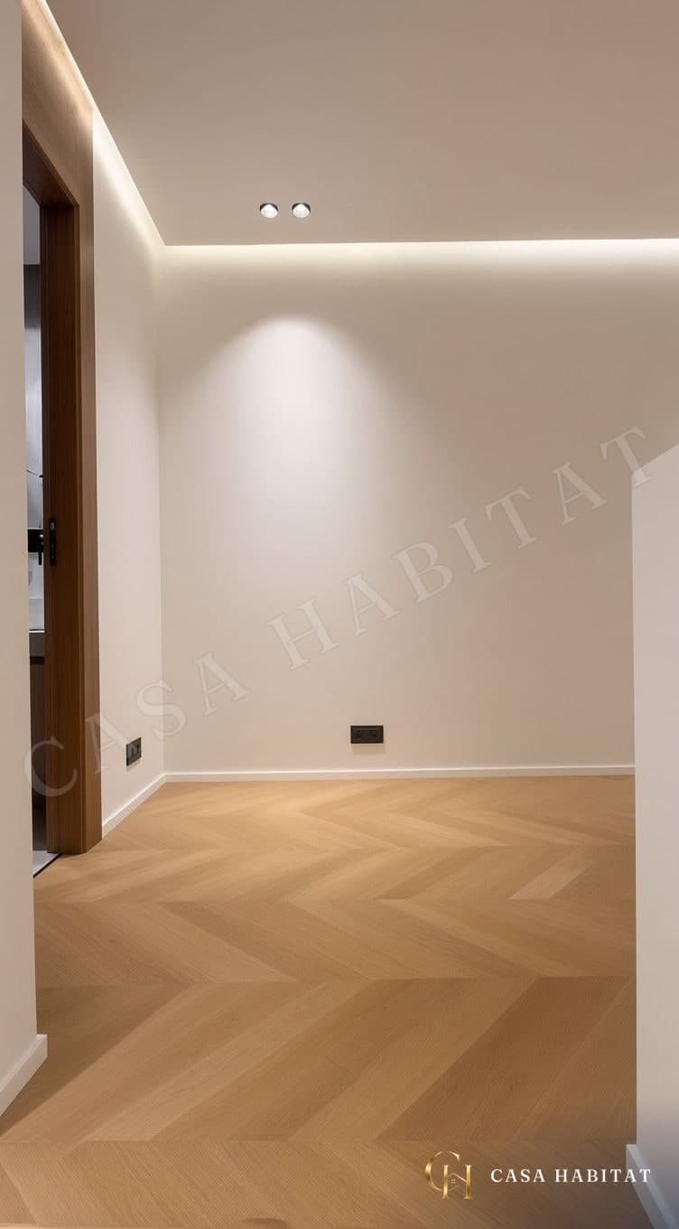 Pièce vide au parquet en chevron, spot lumineux sur le mur blanc