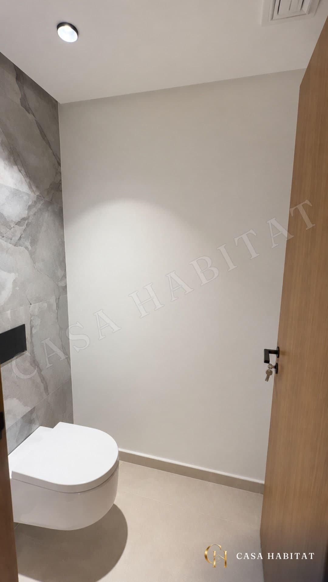 Toilettes suspendues blanches près d'un mur en marbre gris