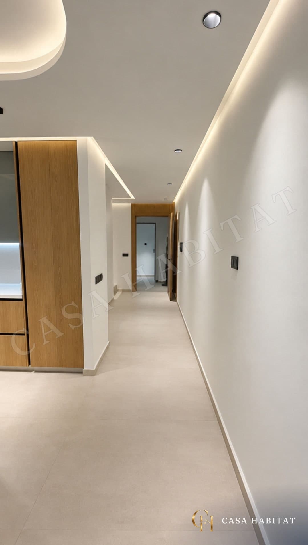 Couloir clair avec meuble en bois, spots et corniche lumineuse