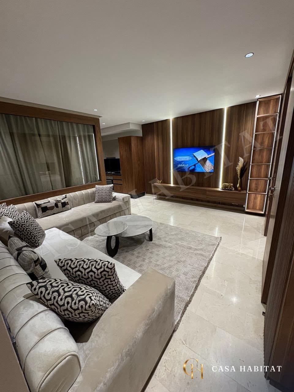 Salon avec canapés crème, tapis gris et meuble TV en bois