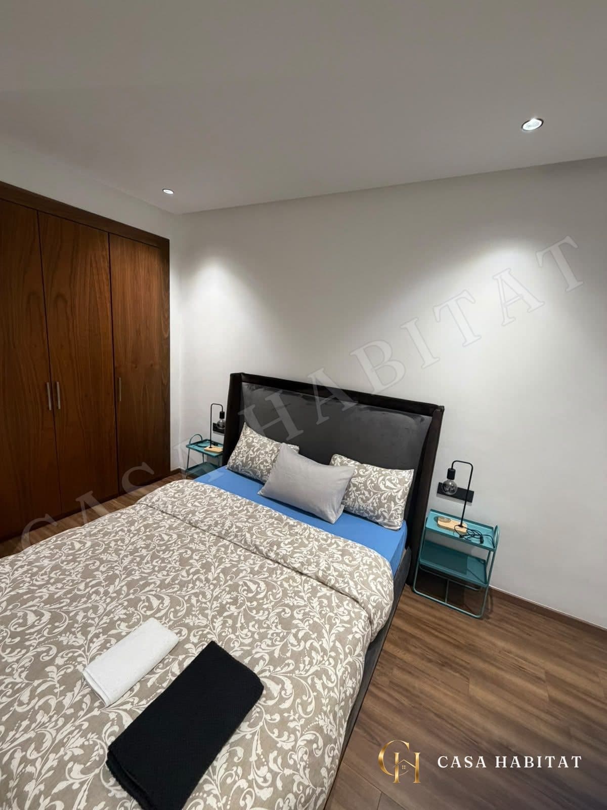Chambre avec lit double, placard en bois et tables de chevet