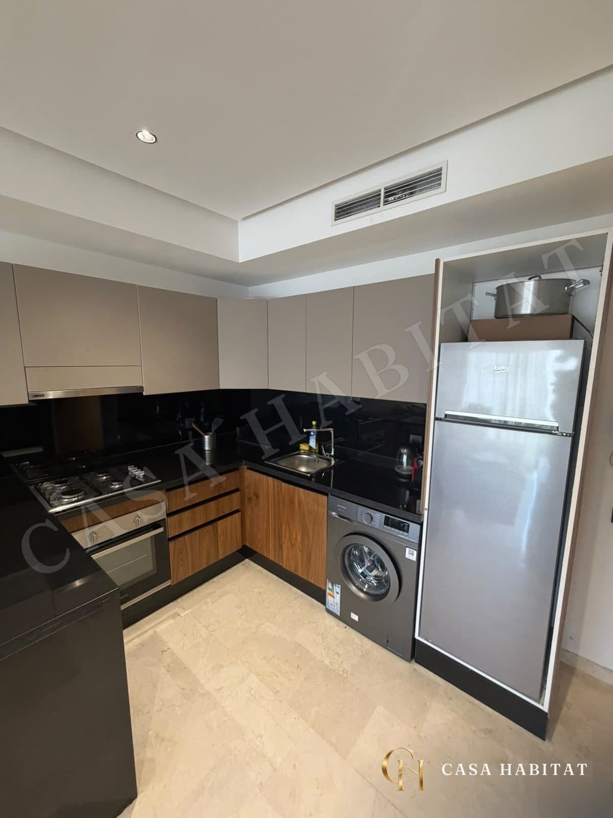 Cuisine en L avec plaque de cuisson, lave-linge et réfrigérateur