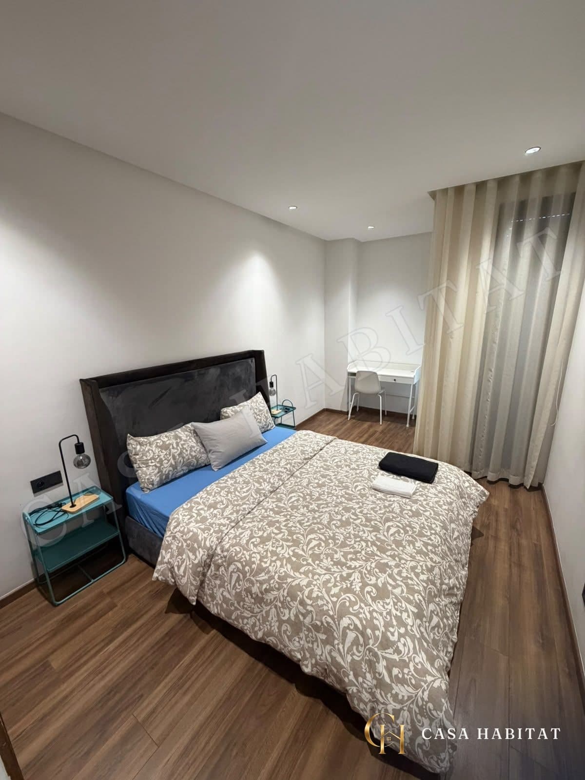 Chambre avec lit double, bureau blanc et rideaux beiges