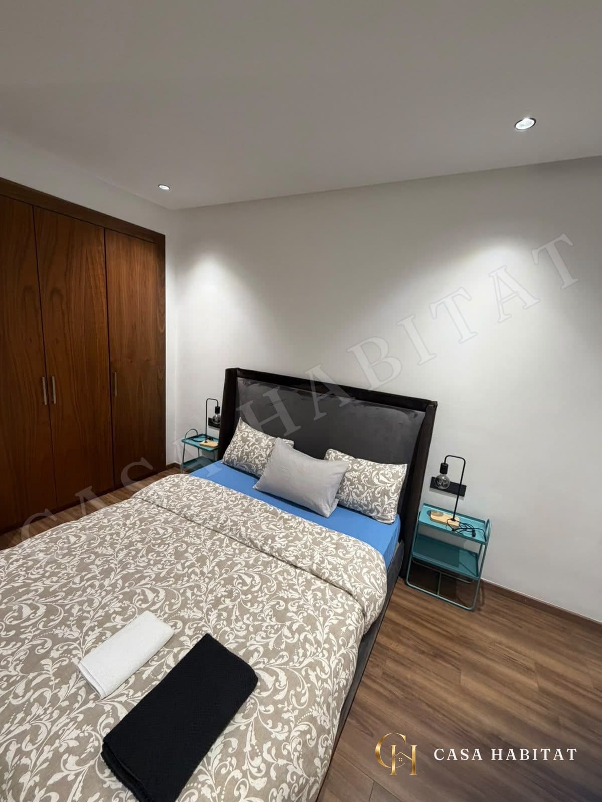 Chambre avec lit double, placard en bois et tables de chevet