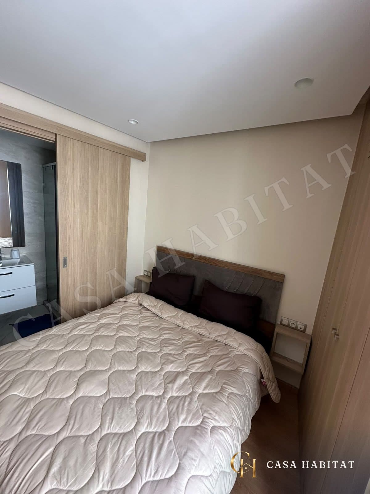 Chambre avec lit double recouvert d'une couette beige