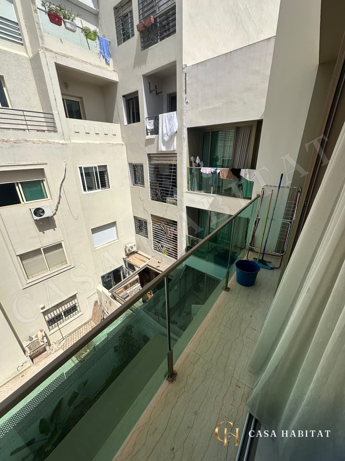 Balcon vitré donnant sur les façades voisines avec étendoir