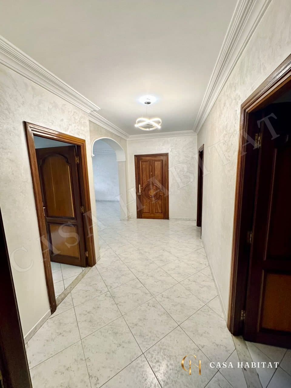 Couloir carrelé avec portes en bois et plafonnier LED