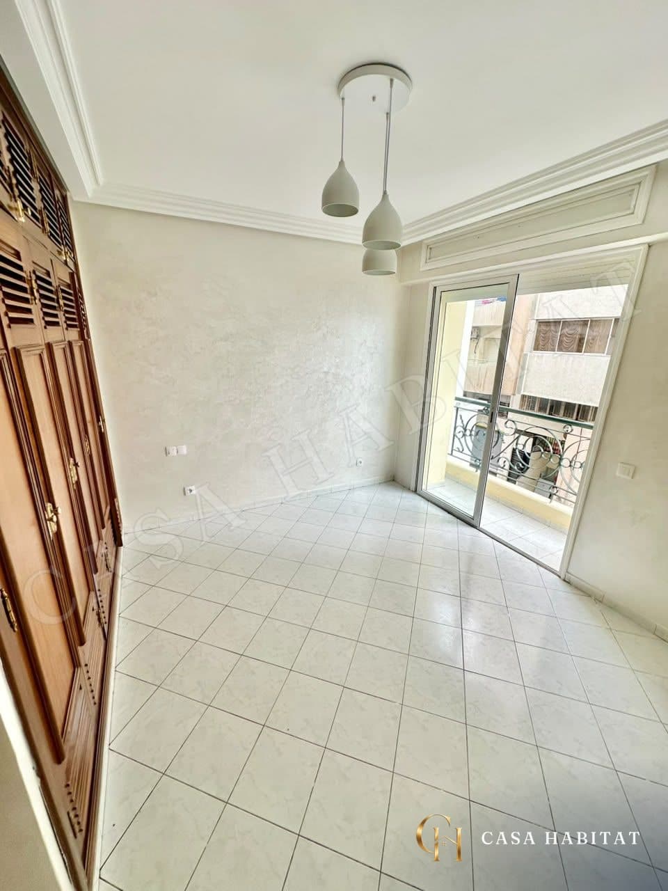 Chambre avec placard en bois et porte-fenêtre sur balcon