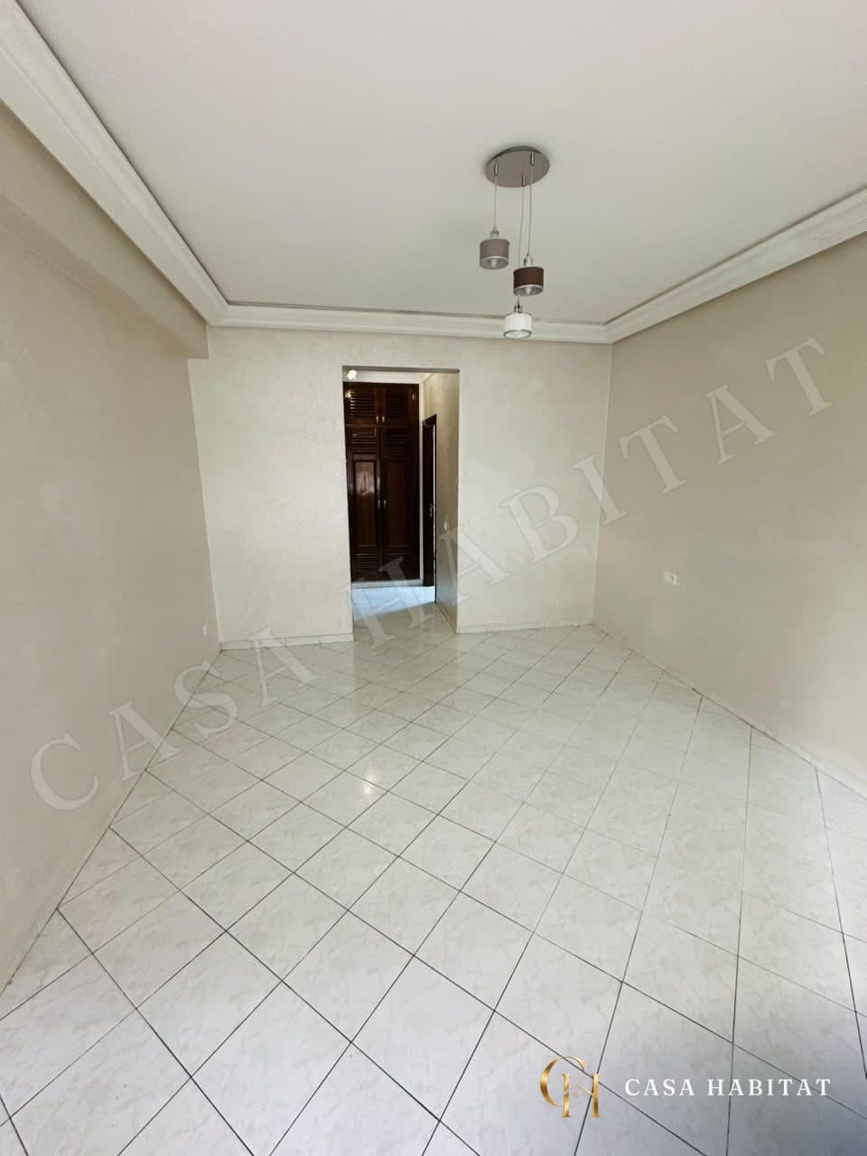 Chambre vide avec carrelage clair et plafonnier suspendu