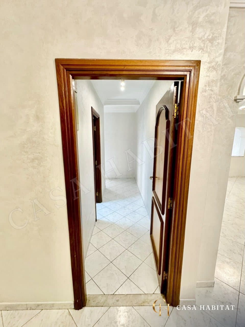 Couloir carrelé vu depuis une porte en bois