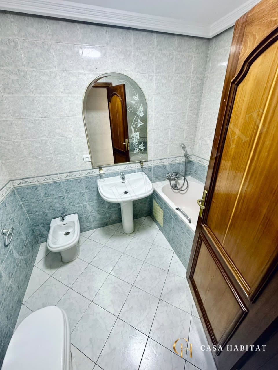 Salle de bain avec lavabo, bidet, baignoire et miroir arrondi