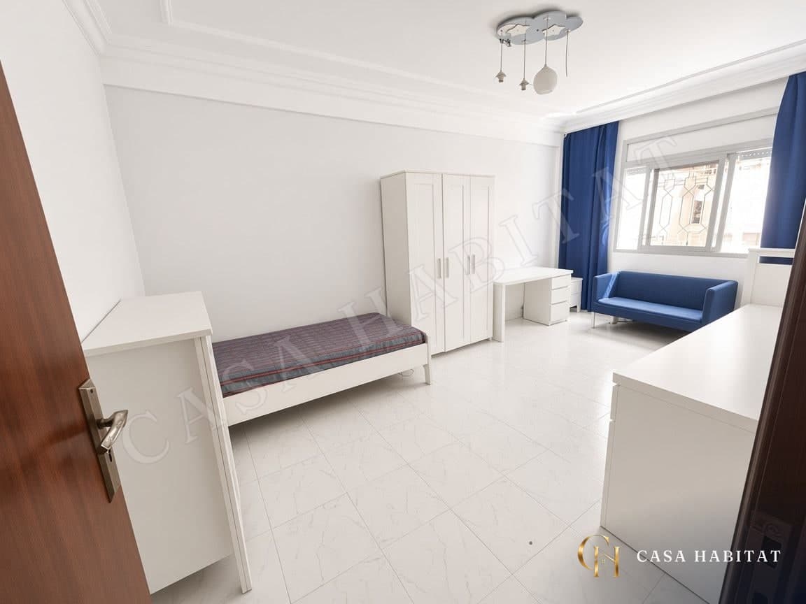 Chambre avec lit simple, bureau blanc et canapé bleu