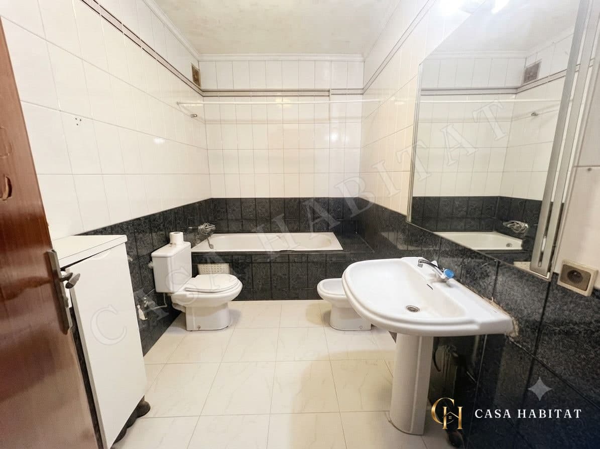 Salle de bain avec baignoire, lavabo et carrelage noir