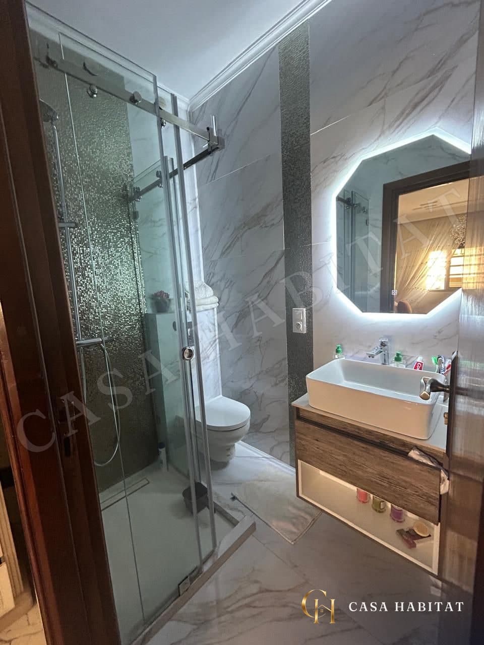 Salle d'eau avec douche en verre et miroir éclairé