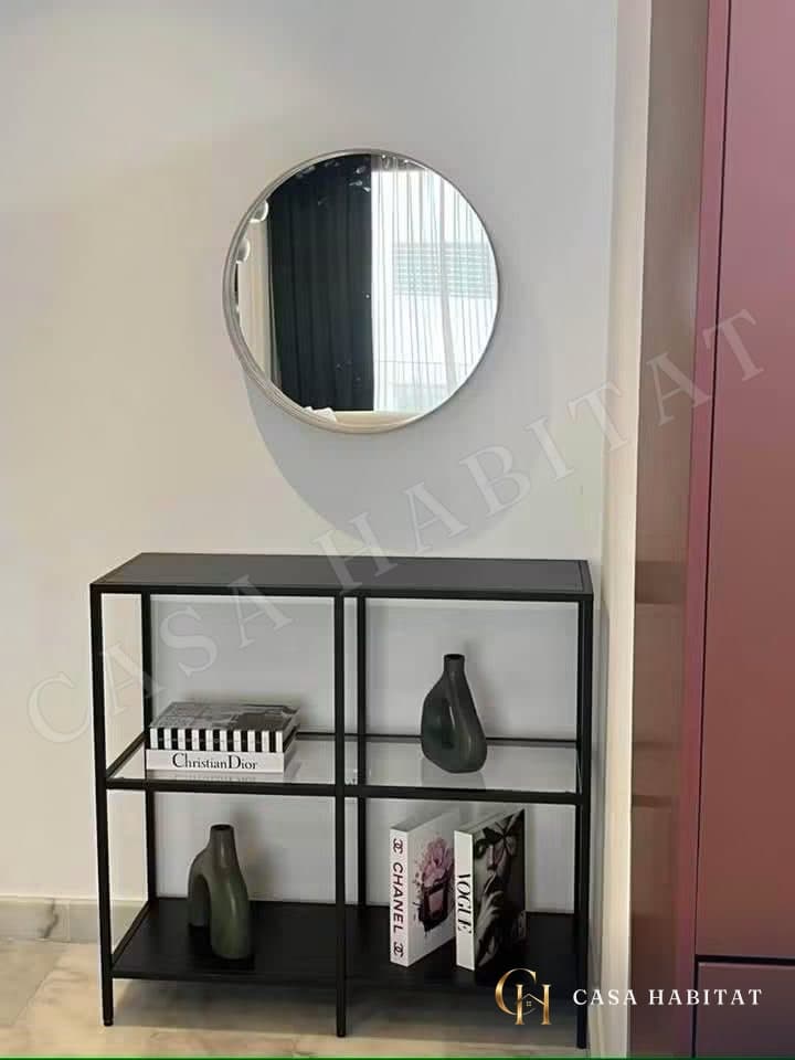Meuble noir avec miroir rond et vases au mur blanc