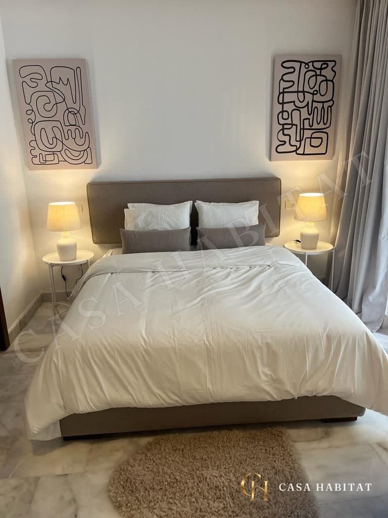 Chambre avec lit blanc, deux tableaux en noir et blanc et lampes de chevet