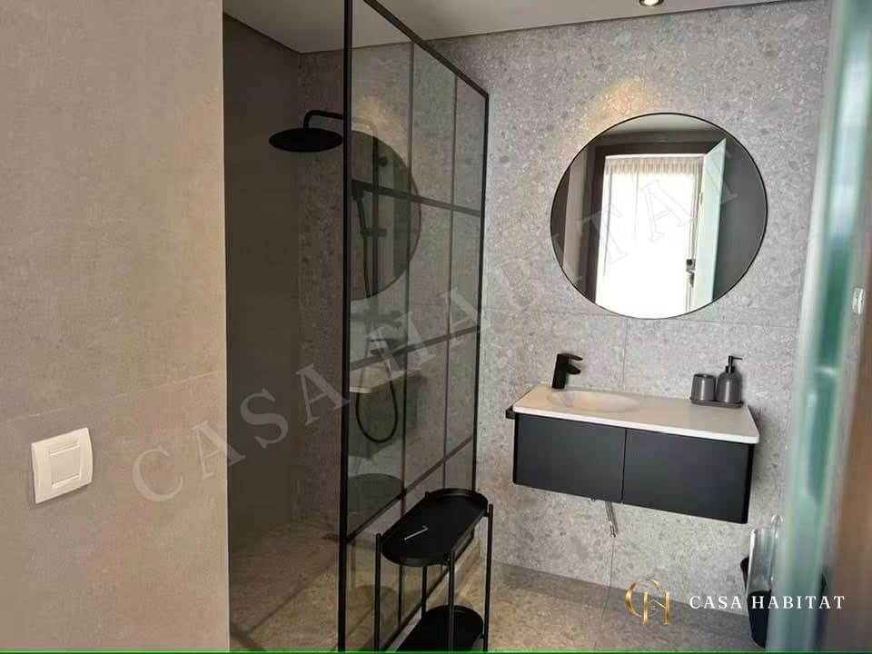 Salle de bain avec douche à l'italienne, vasque suspendue et miroir rond