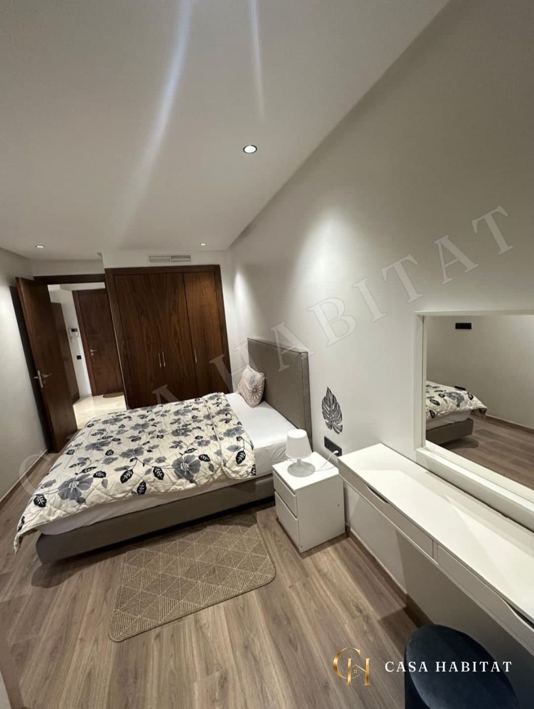 Chambre avec lit double, placard en bois et miroir mural