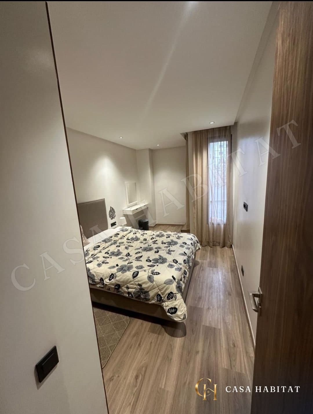 Chambre avec lit à motif floral et rideaux beiges